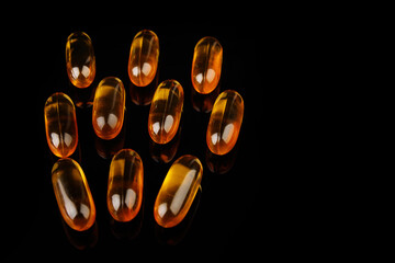 Capsules with fish oil on a black background. The use of vitamin D, omega-3. Health concept