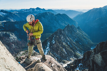Man sorting climbing gear on alpine rock climb in Washington