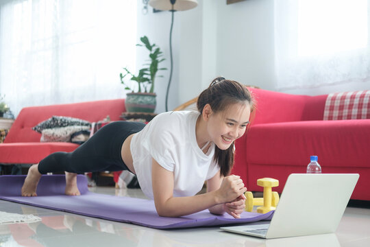 Fit woman doing yoga plank and watching online tutorials.