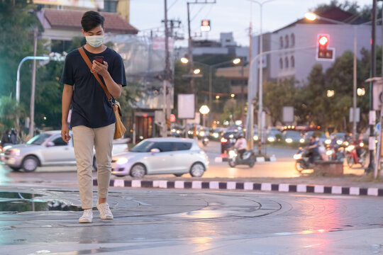 Young man with protective face mask using mobile phone in city s