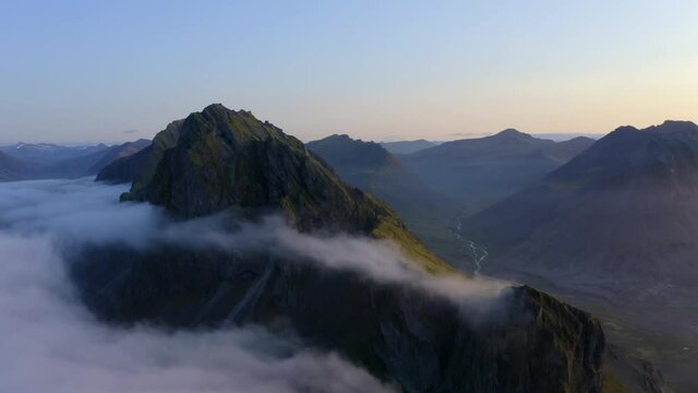 Drone aerial footage of Coastal mountains and cliffs near Stokkness at sunrise with beautiful layer of clouds (cloud inversion) in Iceland
