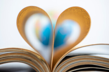 Love to read concept, world and book pages folded into heart shape 