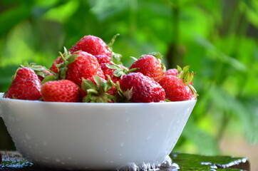 Bowl of organic strawberry in the sink under running water