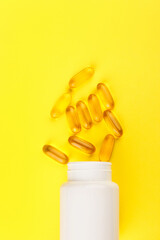 Vitamin D yellow pills on yellow background and white plastic jar. space for text 