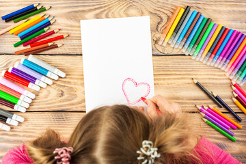 Little girl prepares cards with hearts for Valentine's Day. Drawing is done by a child with colored...