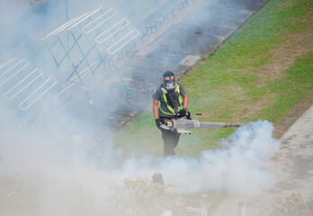 A worker fumigates to kill mosquito larvae to fight against the spread of dengue fever, Zika virus or Malaria at a residential area.
