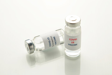 Coronavirus COVID-19 vaccine vials on reflective surface.