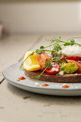 Smoked salmon and avocado on toast, topped with poached egg and dressing