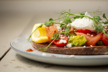 Smoked salmon and avocado on toast, topped with poached egg and dressing