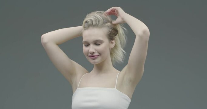 Happy young beautiful woman doing long hair style make ponytail hairstyle getting ready during everyday routine