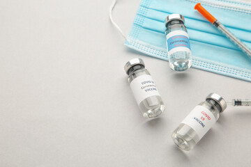 Fototapeta na wymiar Coronavirus COVID-19 vaccine vials, syringe and stethoscope on grey background. Vaccination session and immunity improvement. Covid 19