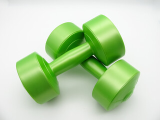 Two green plastic dumbbells of two kilograms for fitness lie on top of each other on a white background