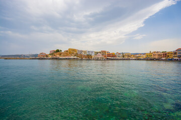 Fototapeta premium azure turquoise blue transparent sea and the city of Chania on the horizon against the blue sky with white clouds on a summer day on the island of Crete in Greece