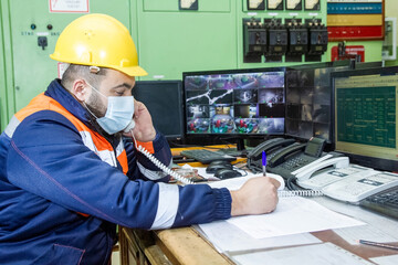 worker with yellow helmet and protective mask at work talking to telephone