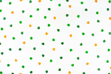 Green orange and white shamrock confetti sparse on white background Happy St. Patrick's Day Spring 17 march backdrop in Irish flag colors with lucky clovers. 