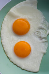 delicious breakfast two scrambled eggs with bright yellow yolks on a green plate