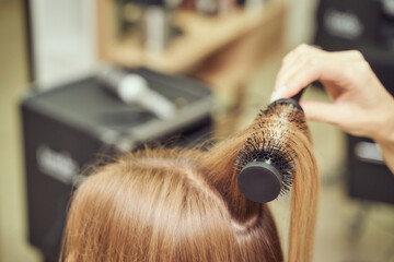 Fototapeta premium Long hair woman. Hairdresser treatment. Repair procedure. Haircut at salon. Bride hairstyle. Master hand with brush. Adult female person. Closeup view. Lady preparation. Blonde dry