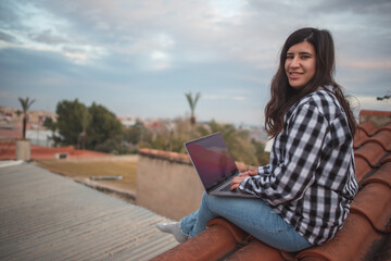 Fototapeta premium Creative girl works from the roof of her house