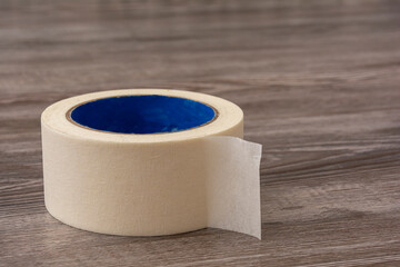 Masking tape on wooden background. Roll of paper tape close-up.