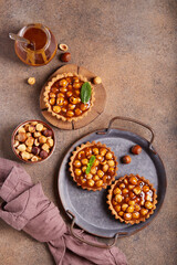 Mini tarts with hazelnuts and caramel cream filling. Sweet homemade dessert.