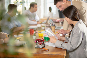 Obraz premium Teamwork. Side view colleagues working together in a office using modern devices during creative meeting. Stationery, laptop, documents. Concept of business, office, finance, open space.