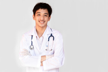 Fototapeta na wymiar A smiling doctor posing with arms crossed on a white background is wearing a stethoscope. Young Asian doctor wearing a white coat.