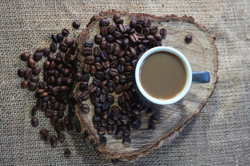 cup and grains of coffee on burlap.
