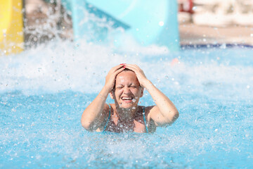 Portrait of woman who has driven down slide in water park. Fun in the water park for adults concept