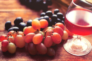 Glass of wine, bottle, grapes on a background of boards.