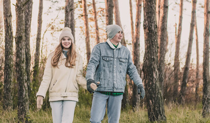 
The guy holds the girl's hand and walk in the pine forest