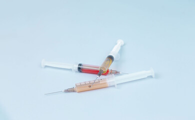 Syringes with different medicines in yellow, red, orange and transparent colors lie on a blue background. The medicine. Vaccine. Covid 19. Coronovirus. An injection. Drugs. The close plan. Top view.