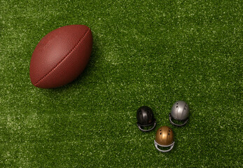 American football ball and little helmets on green grass background. American football decoration