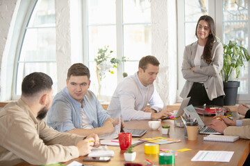 Discussing project. Side view colleagues working together in a office using modern devices during creative meeting. Stationery, laptop, documents. Concept of business, office, finance, open space.