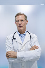 Confident mature older medical healthcare professional doctor standing arms crossed in hospital. Middle aged senior physician, therapist wears white lab coat, stethoscope looking at camera. Portrait