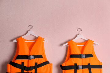 Orange life jackets on pink background. Personal flotation device