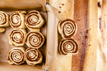 Cinnamon rolls laid on a table being put into a baking tray