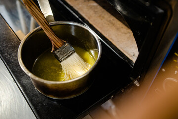 A pan of melted butter with a pastry brush in