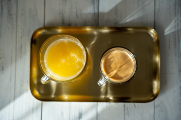 a a cup of coffee with glass of orange juice on a gold tray. sunny morning. Top view. Selective focus. High quality photo
