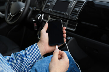 Man charging phone with USB cable in car