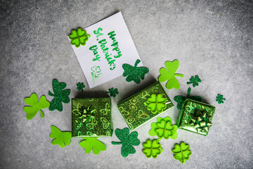 Decorative clover leaves, green gifts box, coins on stone background, flat lay. St. Patrick's Day...