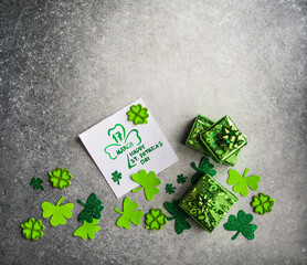 Decorative clover leaves, green gifts box, coins on stone background, flat lay. St. Patrick's Day...