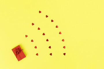 Wi Fi shape made of red gift box and hearts on yellow background. Minimal love concept. Flat lay  style.