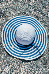 Fototapeta na wymiar Blue striped sun hat on gray stones background.