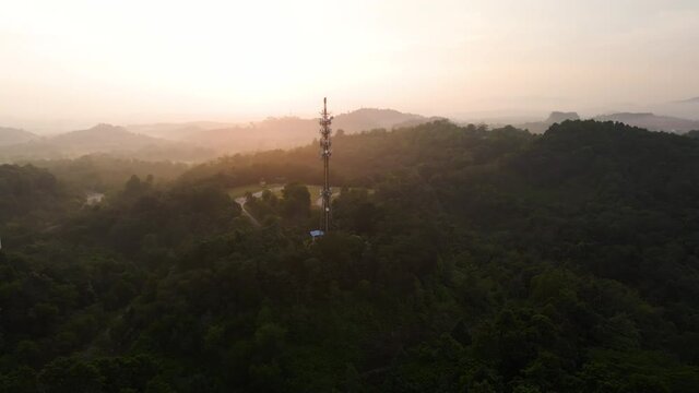 Aerial footage of Communication tower during morning sunrise with clouds, mists and fog