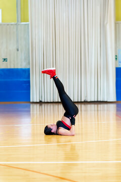 Female fighter in sportswear doing stretching, sitting on floor at gym