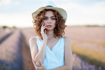 woman with curly hair wearing a hat in a lavender field