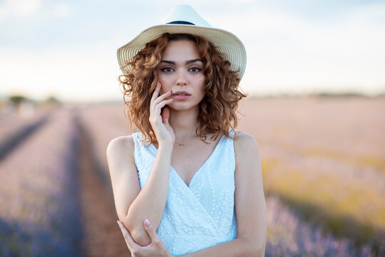 woman with curly hair wearing a hat in a lavender field