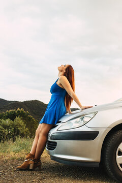 Young Woman Standing Leaning On A Car Looking Up Alone In Nature