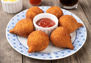 Typical brazilian snack coxinha on a plate over wooden table