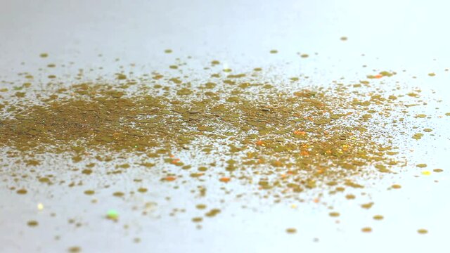 gold sequins and rhinestones pour from above and shimmer beautifully on a white background close-up, festive background
